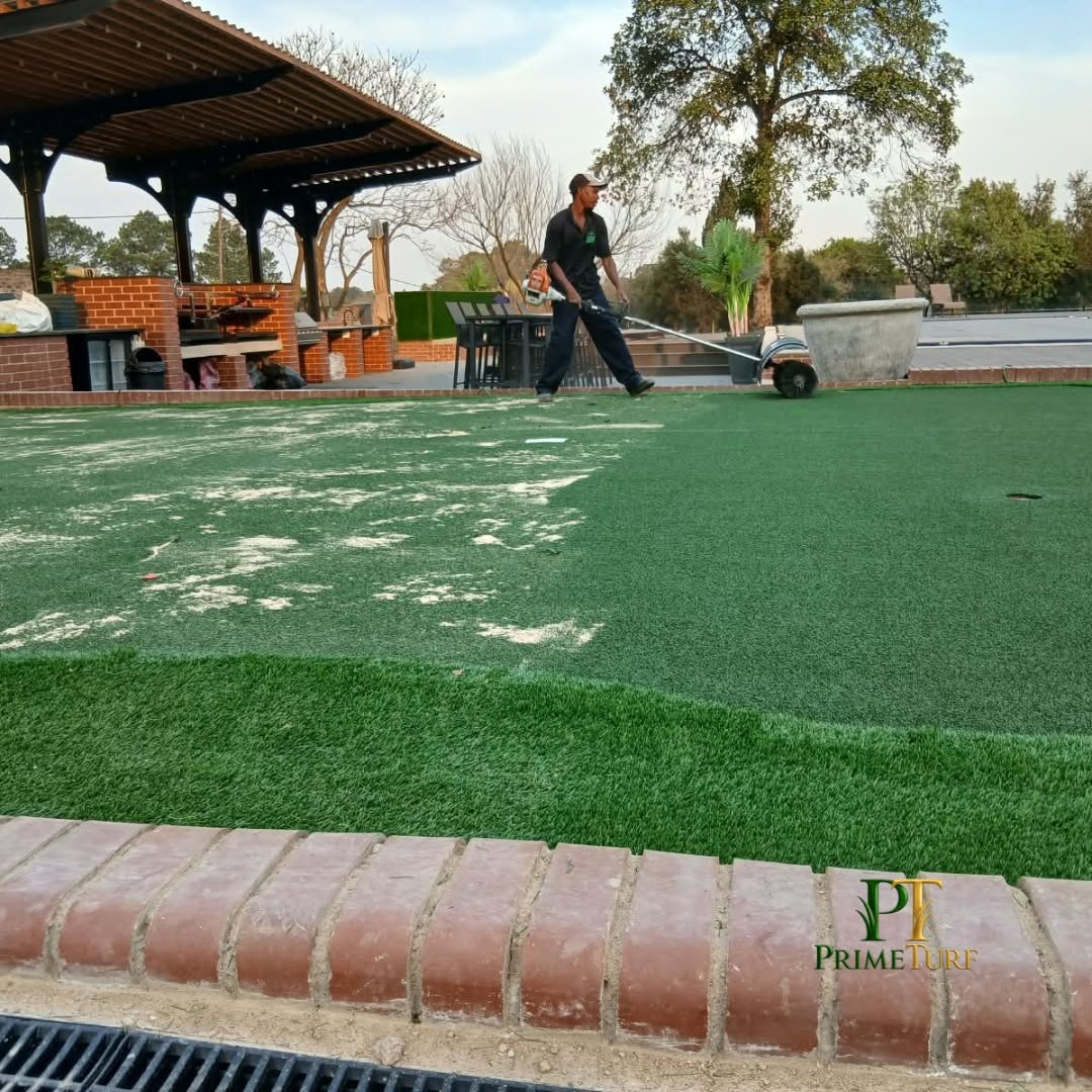 A PrimeTurf installer power-brushing silica infill into a newly laid putting green