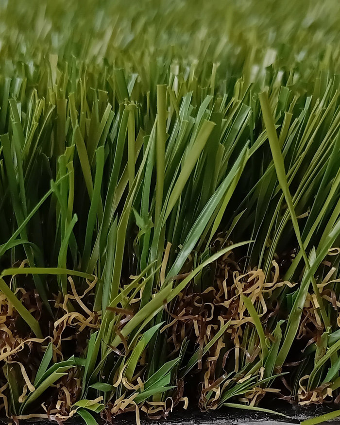 Close-up cross-section of artificial grass showing green blades and brown thatch layer